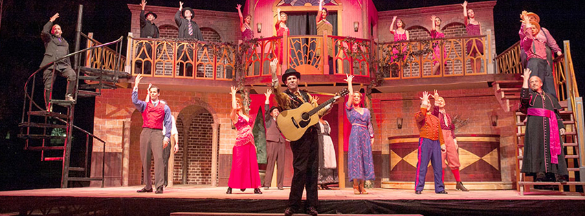 Michael FAulkner as the character "Feste" in William Shakespeare's "Twelfth Night," appearing with a guitar in front of an entire cast dressed in 1920's attire